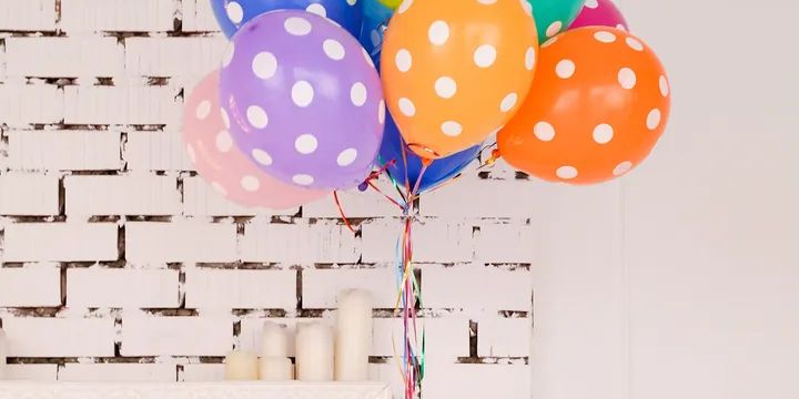 Colorful balloons against a white brick wall