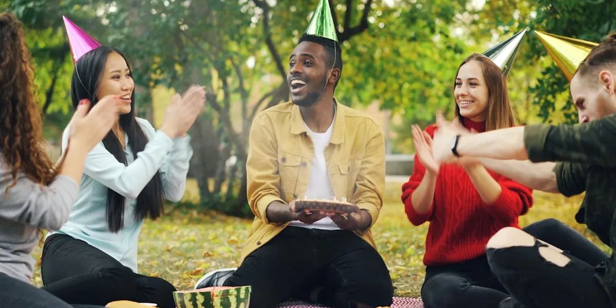 Friends celebrating a birthday at a picnic in a park