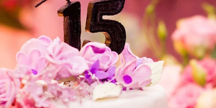 A pink birthday cake with flowers and number candles